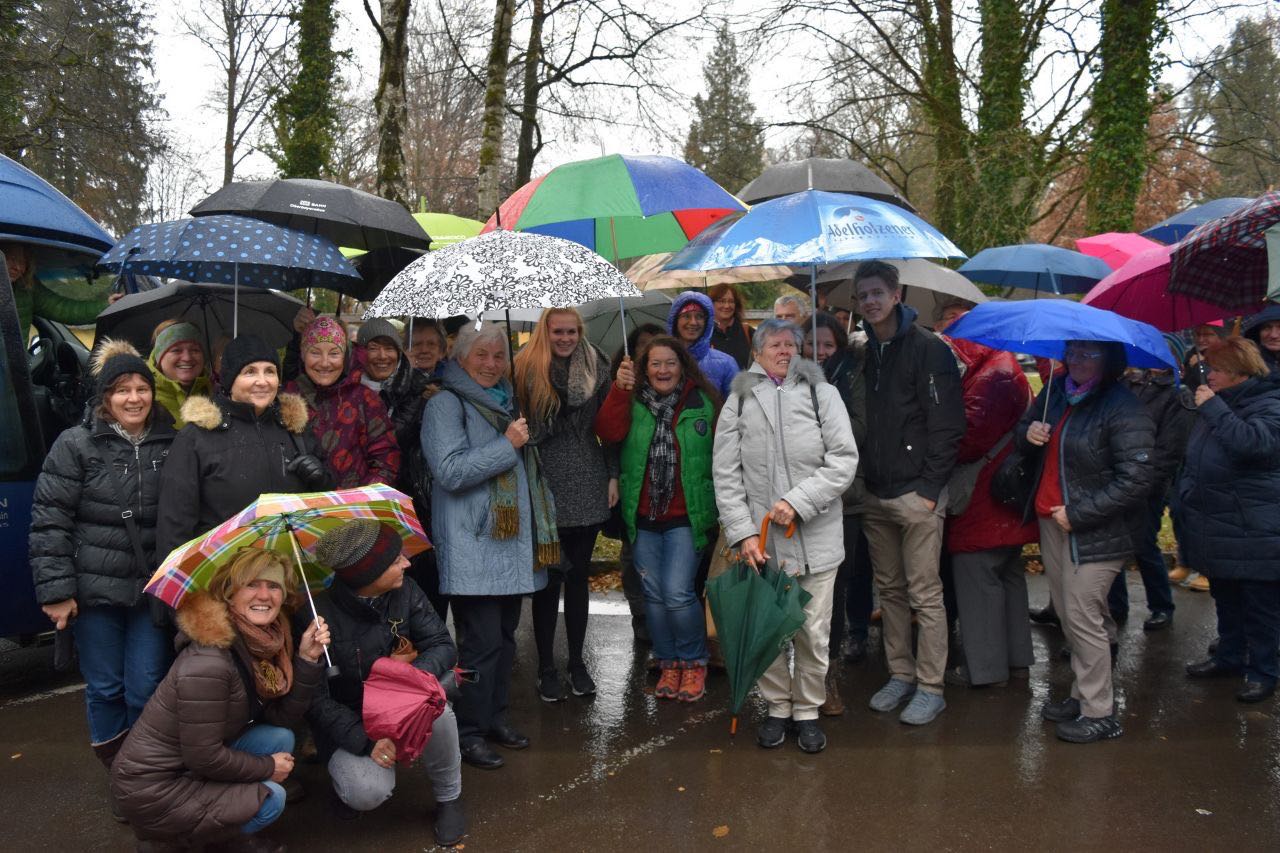 Ein Gruppenfoto, wo die Menschen Regenschirme haben, da es sehr regnet.